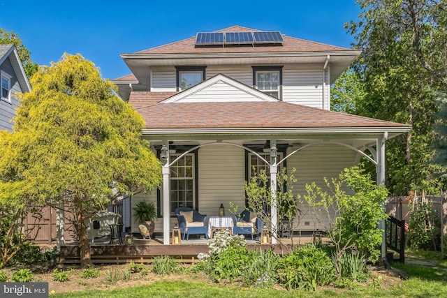 back of property with fence, a shingled roof, and solar panels