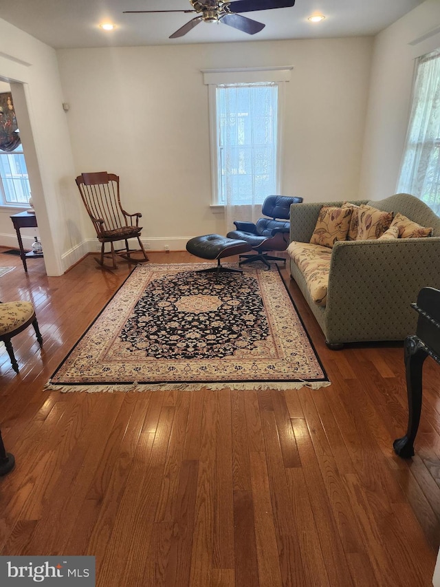 living area with wood-type flooring and ceiling fan