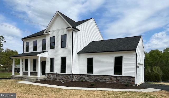 view of front of house featuring stone siding, a porch, board and batten siding, and roof with shingles