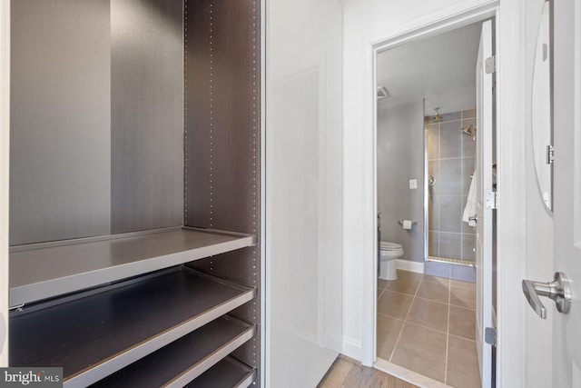 bathroom featuring toilet, a shower stall, baseboards, and tile patterned flooring