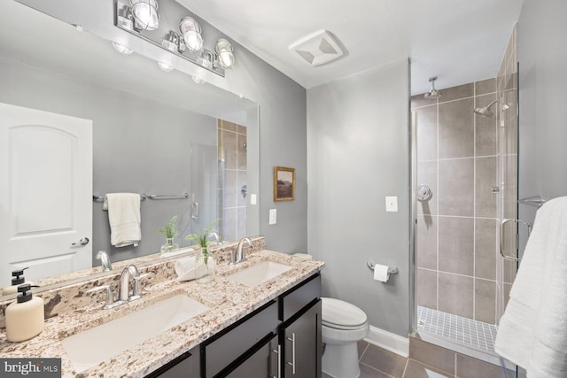 full bathroom featuring toilet, a shower stall, a sink, and tile patterned floors