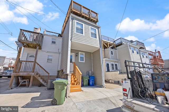 rear view of property with entry steps, a balcony, and central air condition unit