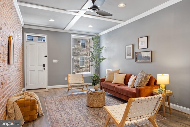 living area with brick wall, crown molding, baseboards, and wood finished floors