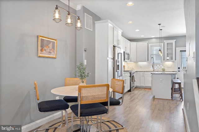 dining room featuring light wood-type flooring, visible vents, baseboards, and recessed lighting