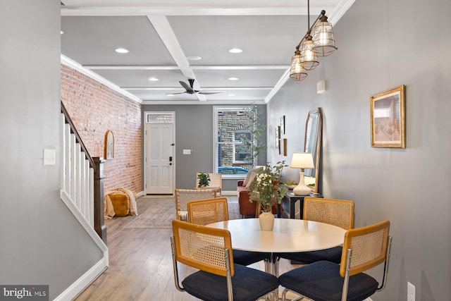 dining area featuring crown molding, stairway, light wood-style floors, brick wall, and coffered ceiling