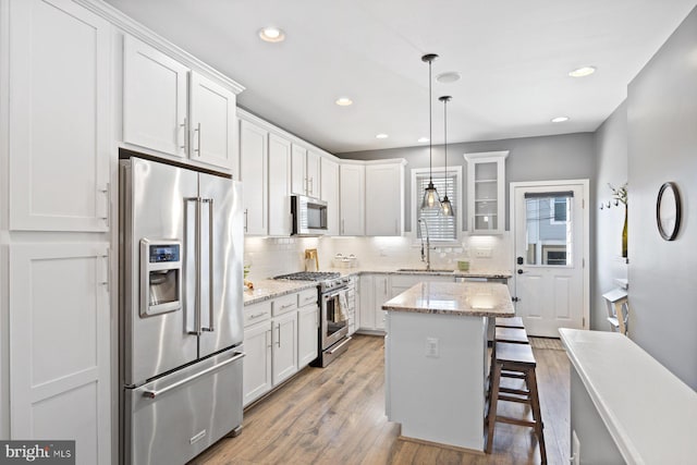 kitchen with decorative backsplash, premium appliances, a breakfast bar, wood finished floors, and a sink