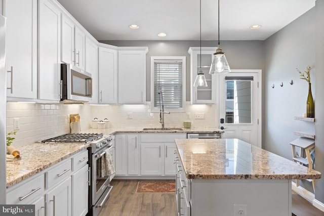 kitchen with stainless steel appliances, dark wood-style flooring, a sink, white cabinets, and a center island