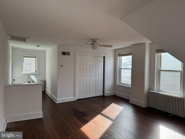 interior space featuring dark wood-type flooring, plenty of natural light, and radiator