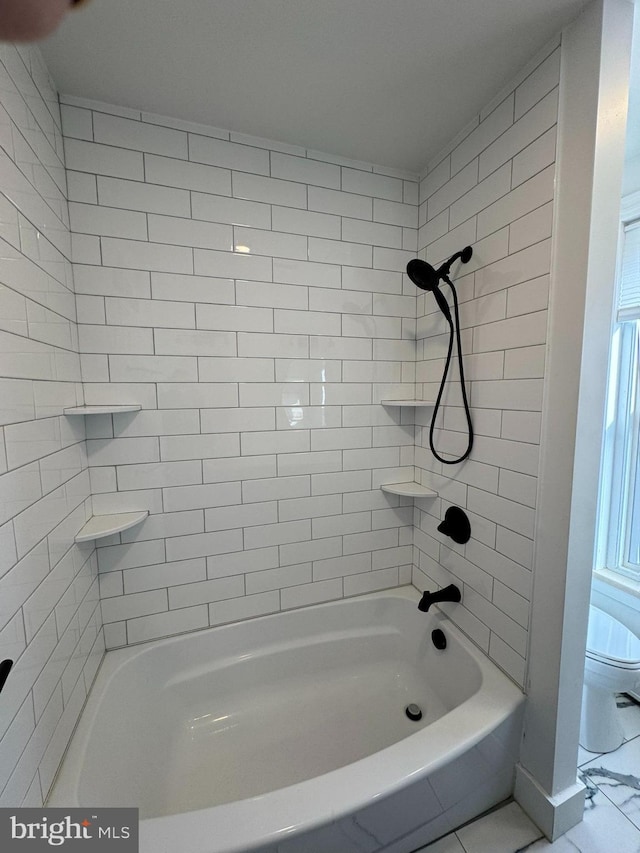 bathroom with tiled shower / bath combo and toilet