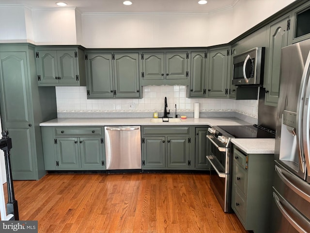 kitchen with appliances with stainless steel finishes, tasteful backsplash, sink, light hardwood / wood-style floors, and crown molding