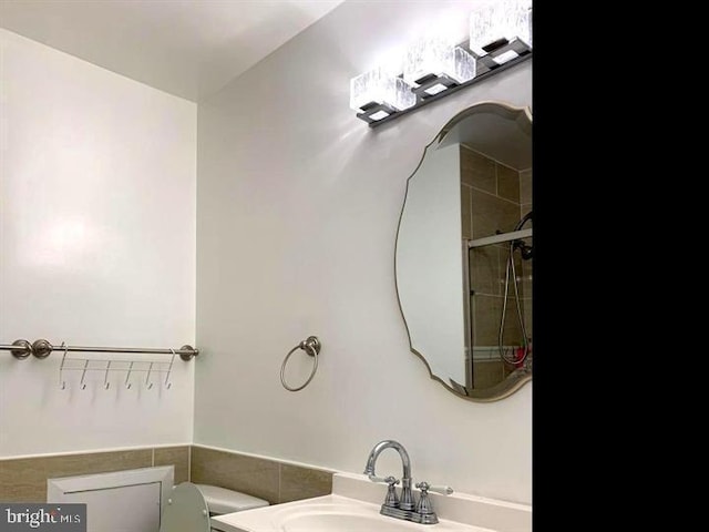 bathroom with sink, a tile shower, and toilet