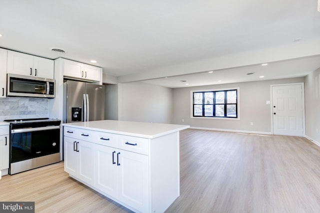 kitchen featuring white cabinetry, stainless steel appliances, a center island, tasteful backsplash, and light wood-type flooring