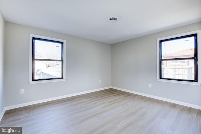 spare room with plenty of natural light and light hardwood / wood-style flooring