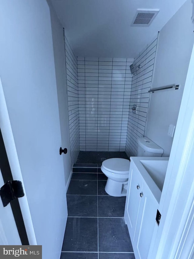 bathroom with vanity, toilet, tile patterned flooring, and a shower