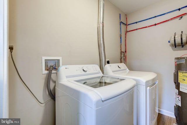 laundry room featuring washing machine and clothes dryer, wood-type flooring, and electric water heater