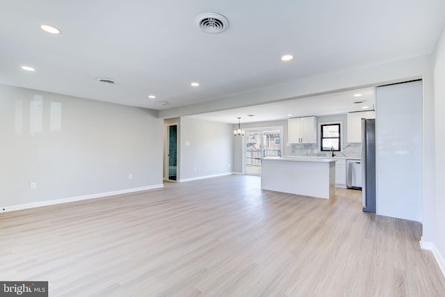 unfurnished living room featuring a chandelier, sink, and light hardwood / wood-style flooring