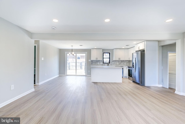 kitchen with decorative light fixtures, white cabinetry, stainless steel fridge, decorative backsplash, and range