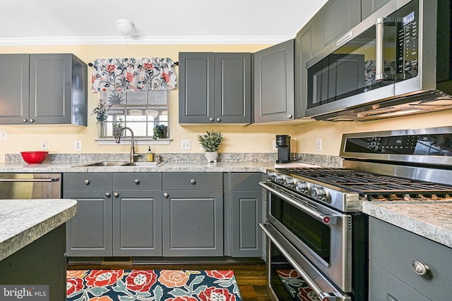 kitchen with gray cabinetry, sink, crown molding, and appliances with stainless steel finishes