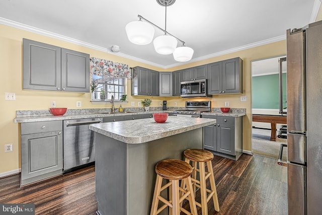 kitchen featuring sink, gray cabinets, appliances with stainless steel finishes, ornamental molding, and a kitchen island