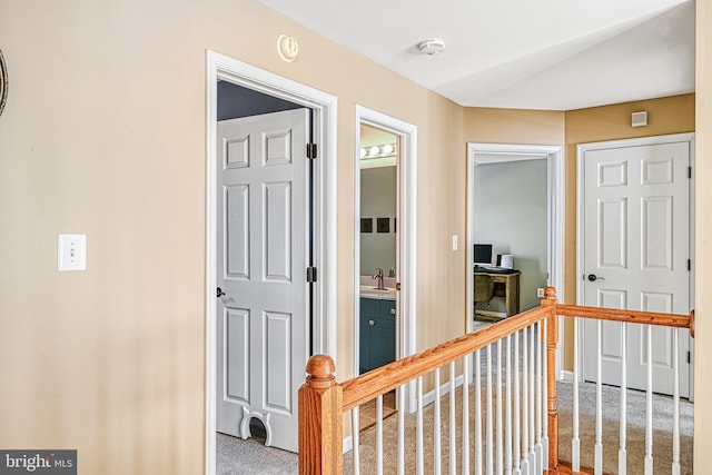 hall featuring vaulted ceiling, carpet floors, and sink