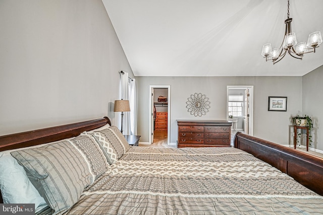 bedroom with a spacious closet, vaulted ceiling, a closet, and a chandelier