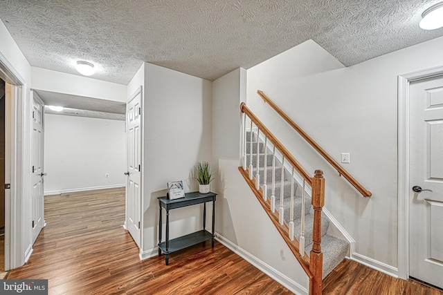 stairs featuring hardwood / wood-style flooring and a textured ceiling