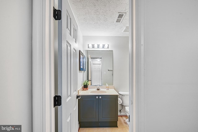 bathroom with vanity, a textured ceiling, and toilet