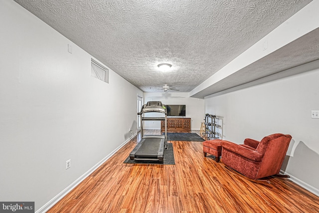 workout room featuring wood-type flooring and a textured ceiling