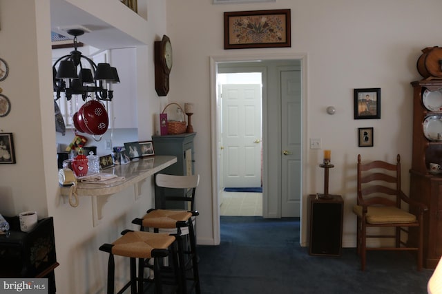 kitchen with a notable chandelier, dark carpet, and a breakfast bar