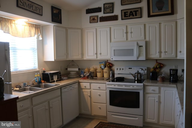 kitchen featuring sink, white appliances, light tile patterned floors, and white cabinets