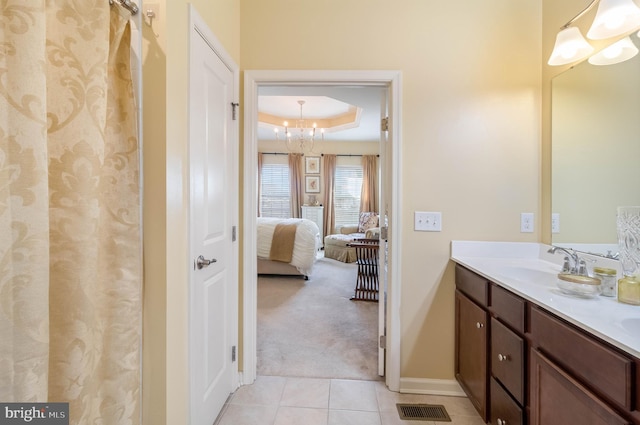 bathroom featuring tile patterned flooring, vanity, an inviting chandelier, and a tray ceiling