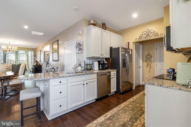 kitchen featuring sink, a breakfast bar, appliances with stainless steel finishes, light stone counters, and white cabinets