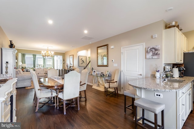 dining space with sink, an inviting chandelier, and dark hardwood / wood-style flooring