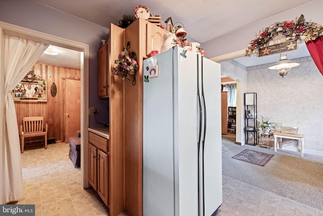 kitchen with white refrigerator, light carpet, and wooden walls