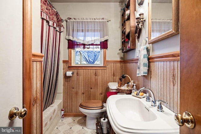 full bathroom with shower / bathtub combination with curtain, toilet, sink, and wood walls