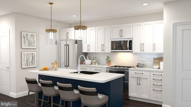 kitchen with sink, appliances with stainless steel finishes, white cabinetry, an island with sink, and decorative light fixtures