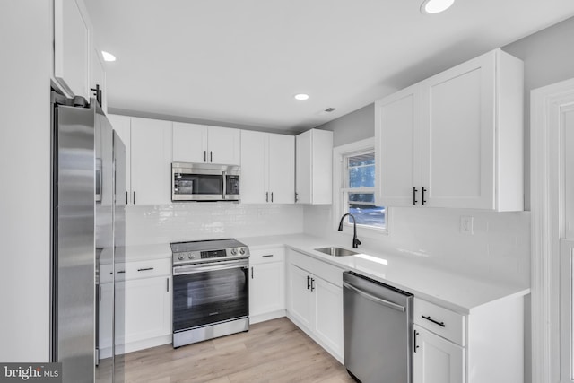 kitchen with stainless steel appliances, white cabinetry, and sink