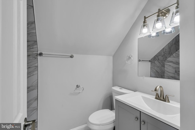 bathroom featuring vanity, toilet, and vaulted ceiling