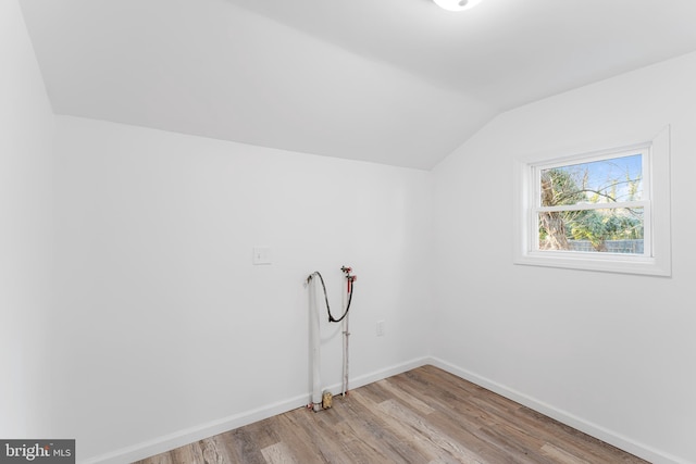 additional living space with baseboards, lofted ceiling, and wood finished floors