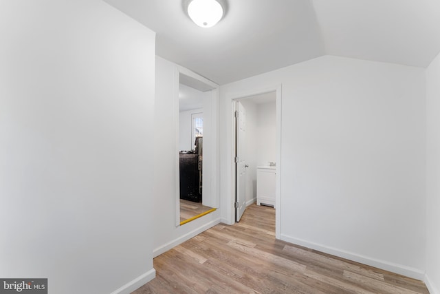 corridor featuring vaulted ceiling, baseboards, and wood finished floors