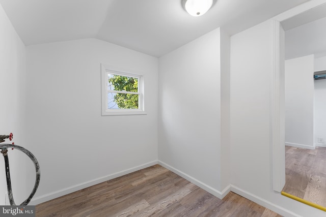 interior space with baseboards, wood finished floors, and vaulted ceiling
