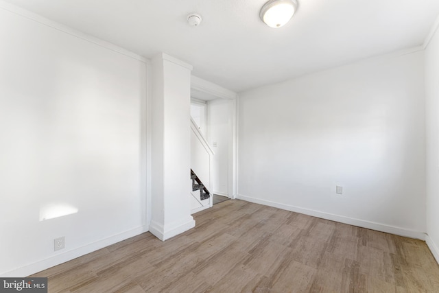 basement with stairway, baseboards, and light wood-style floors