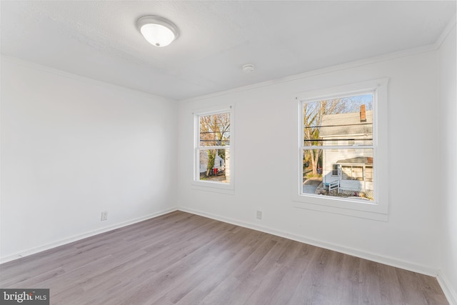 unfurnished room with wood finished floors, a healthy amount of sunlight, and baseboards