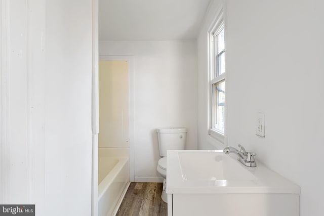 full bath with toilet, a tub to relax in, wood finished floors, and vanity