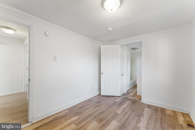 unfurnished room featuring baseboards, a textured ceiling, and light wood finished floors