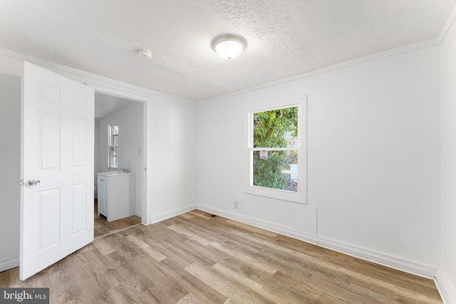 unfurnished room featuring light wood-style floors, baseboards, and a textured ceiling