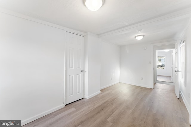 spare room with baseboards and light wood finished floors