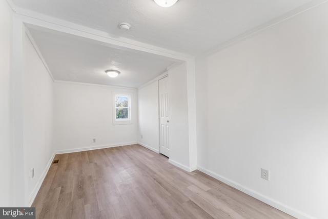 empty room featuring ornamental molding, baseboards, and wood finished floors