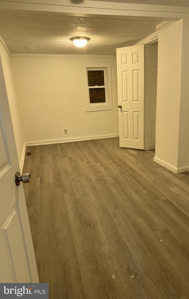 empty room with dark wood-type flooring and a textured ceiling