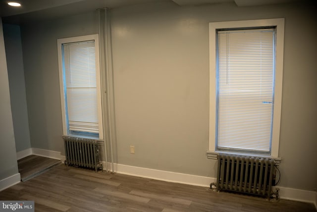 unfurnished room with dark hardwood / wood-style floors and radiator